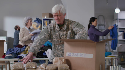 Wall Mural - Military officer pack food in boxes for donation in volunteering center