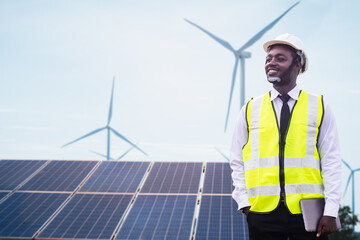 african engineer manager stand holding tablet front the solar photovoltaic and wind turbines generat