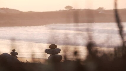 Wall Mural - Rock balancing on pebble beach, Monterey 17-mile drive, California coast, USA. Stable pyramid stacks of round stones, sea ocean water waves crashing at sunset. Serenity harmony, calm zen meditation.