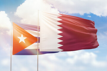 Sunny blue sky and flags of qatar and cuba