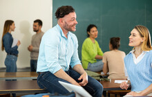 Adult Students Of University Chatting On Break Sitting At Desks