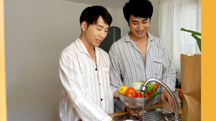 Happy Asian gay couple homosexual cooking together in kitchen wash vegetable organic salad healthy home cook. Asian two Man hands wash cleaning fresh vegetable in kitchen.  LGBTQIA lifestyle concept