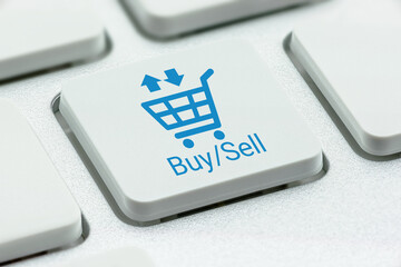 Wall Mural - Buy and sell products online, complete ecommerce solutions, business concept : Shopping cart logo and the words BUY SELL on a computer keyboard push button. Exchanging products in a shopping basket.