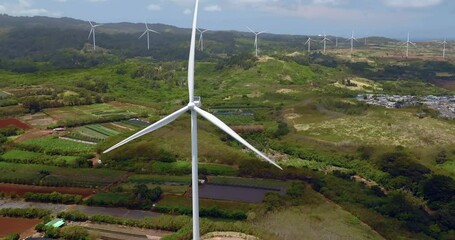 Wall Mural - Aerial view of single wind turbine on green meadows with mountains in background , Oahu Island, Hawaii. Slow motion close up view
