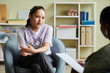 canvas print picture Teenage girl sitting on armchair and talking about her problems to psychologist during consultation at office