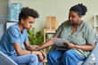 canvas print picture - African psychologist supporting depressed teenage boy feeling guilty about behavior during therapy at office