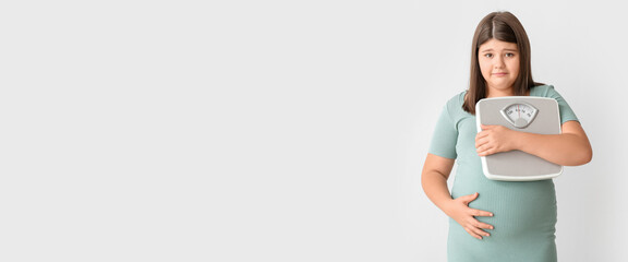 Sad overweight girl with measuring scales on light background with space for text