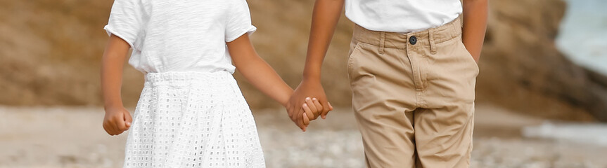 Wall Mural - Little African-American brother and sister holding hands on sea beach