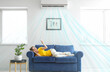 © Pixel-Shot - Young woman switching on air conditioner while lying on sofa at home