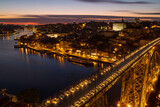 Fototapeta Most - The cityscape of Porto with a bridge in the foreground at sunset and nightfall