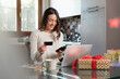 © Westend61 - Happy woman with credit card doing online shopping through smart phone at home