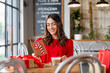 © Westend61 - Happy beautiful woman reading Christmas card sitting in cafe
