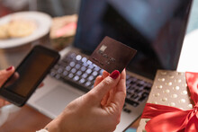 Hands Of Woman Holding Credit Card And Smart Phone By Christmas Present At Home