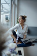 © Westend61 - Happy businesswoman holding laptop sitting on widow sill in office