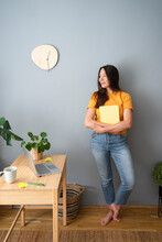 Smiling Woman Looking Away Holding Diary In Front Of Gray Wall