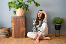 Contemplative Woman With Head In Hands Sitting On Floor At Home
