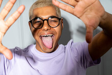 Young Man Wearing Eyeglasses Sticking Out Tongue