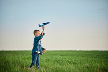 Boy Throwing Airplane Toy In Field On Weekend