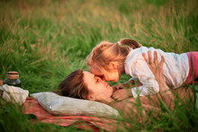 Mother And Daughter Rubbing Noses Lying On Grass At Picnic