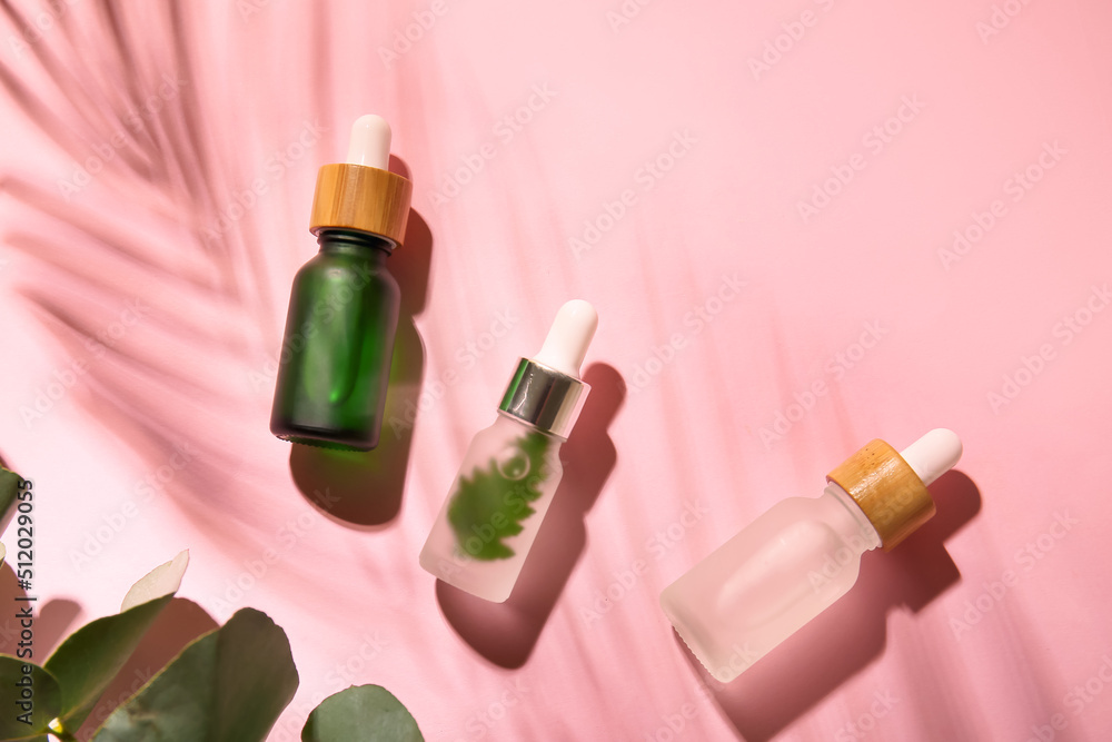 Bottles of natural serum on pink background