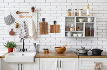 Kitchen Counters With Utensils And Shelf Unit On White Brick Wall