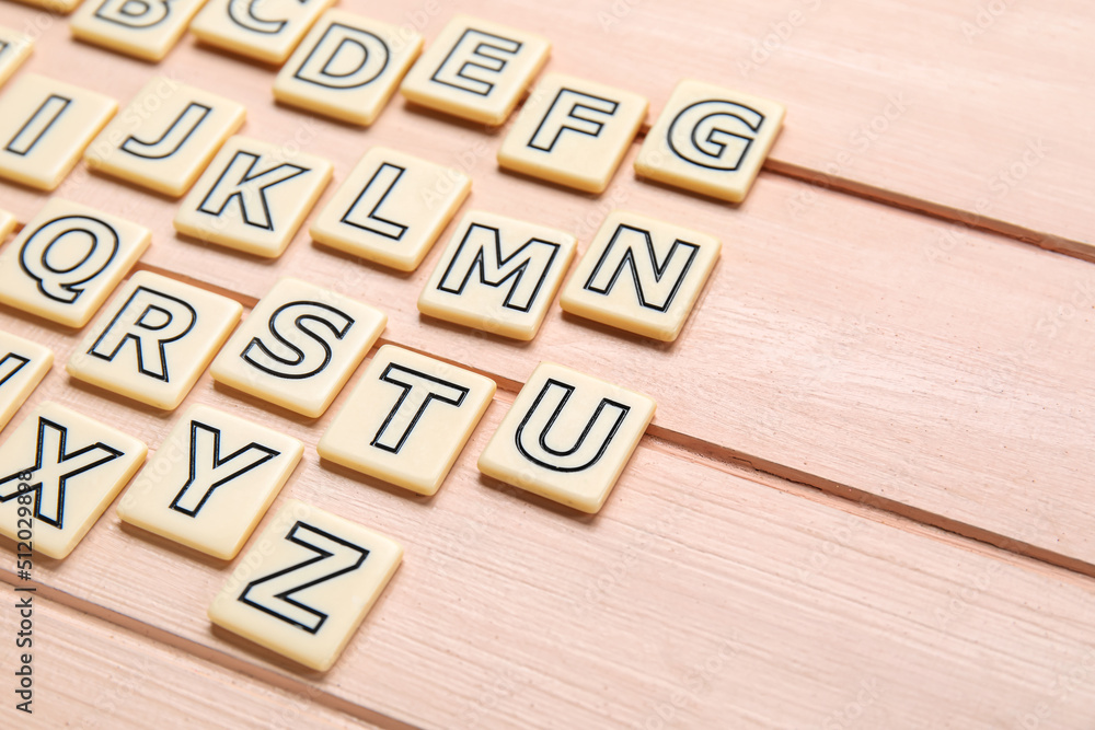 Different letters on pink wooden background. Alphabet concept