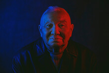 Senior Man's Face Illuminated With Red And Blue Neon Light Against Black Background
