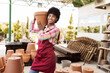 © Westend61 - Smiling gardener carrying pot standing in warehouse