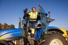 Happy Female Farmer Gesturing Peace Sign Standing In Tractor