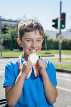 Smiling Boy Showing Golden Medal On Sunny Day