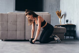 Fit woman working out with ab exercise wheel at home.