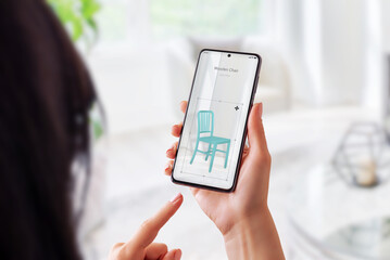 Wall Mural - woman with augmented reality app sets up a wooden chair in living room. virtual furniture placement 