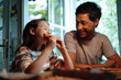 © Westend61 - Smiling man looking at daughter eating food at home