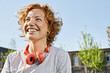 © Westend61 - Portrait of happy young woman with headphones in urban surrounding