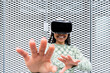 © Westend61 - Smiling young woman wearing virtual reality simulator gesturing in front of metal wall