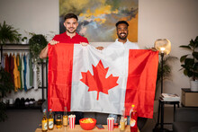 Happy Young Men Standing With Canadian Flag At Home
