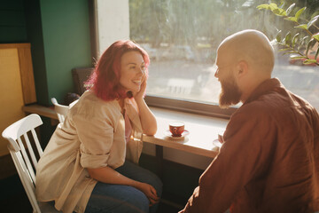 Wall Mural - Happy couple having conversation while drinking coffee in cozy coffeehouse.