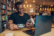 © Zamrznuti tonovi - African american man using laptop while drinking coffee in a cafe