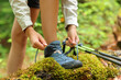 Trekker tying shoelaces of boots in a forest