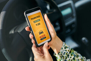 Woman using mobile parking app on smartphone. Driver using smartphone to pay for parking. Car park application on mobile phone. Paying for parking using fast payment online