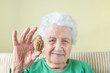 © berna_namoglu - closeup wrinkled hand of a senior woman holding whole walnut between her fingers