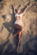 © Itxu - Fit body blond teenage woman dressed in a cream colored bikini lying on the sand of a Mediterranean beach in Guardamar, Alicante, Spain, enjoying sunbathing on her summer vacation.