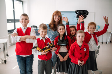 Sticker - A group of school children with teacher learning about eco-friendly renewable sources of energy, looking at camera