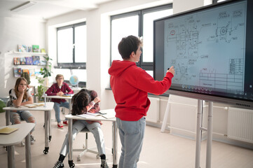 College student explaining some ideas on a touch TV in classroom.