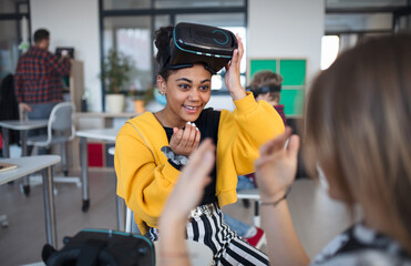 Wall Mural - happy student wearing virtual reality goggles at school in computer science class, playing with her 