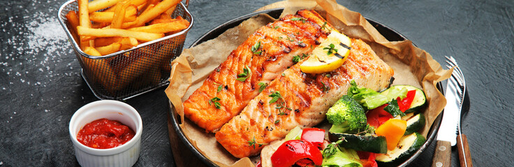 Canvas Print - Salmon steak with vegetables on dark background.