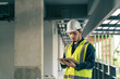 © ME Image - Architect working use BIM technology and digital construction application on digital tablet. Portrait Asian man Civil Engineer working in construction site.