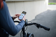 Courier riding a bicycle and looking on the cellphone asnd using delivery app, sustainable transport concept