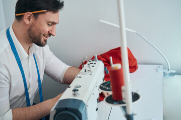 Wall Mural - Creative young tailor working with equipment in atelier