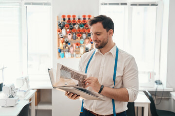 Wall Mural - Smiling tailor with fabrics catalog in atelier